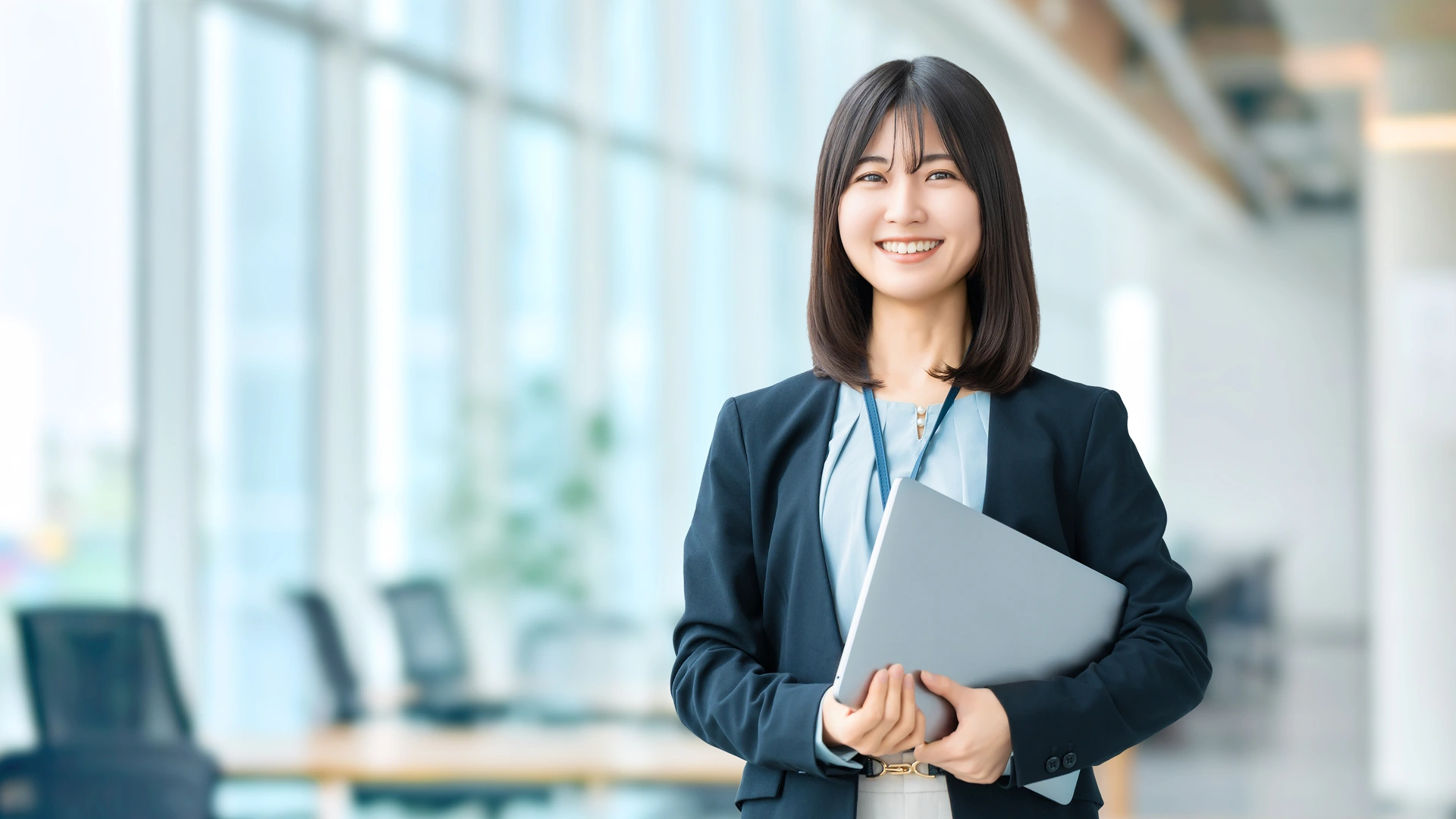 自然光の入るオフィスで笑顔を見せる女性(イメージ)